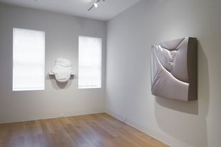 Two pieces of white, 3D artwork in a white gallery