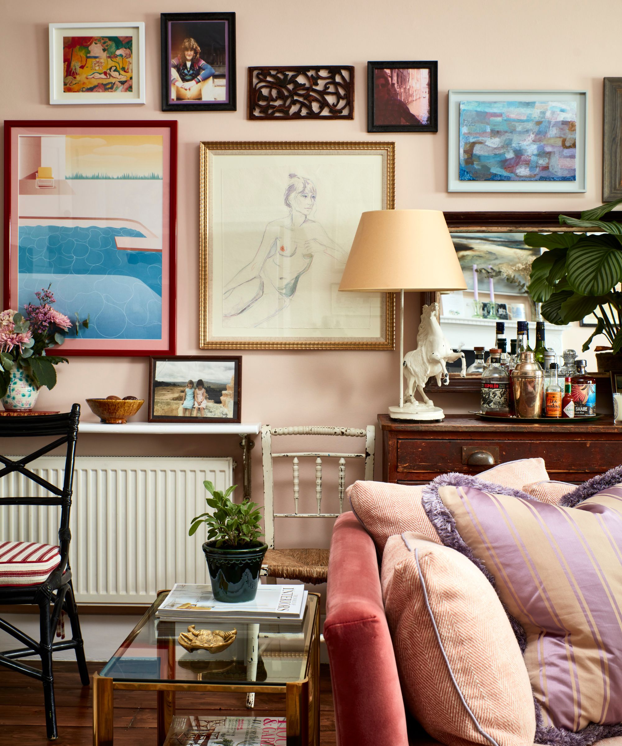eclectic pale pink living room decorated with a collected mural wall