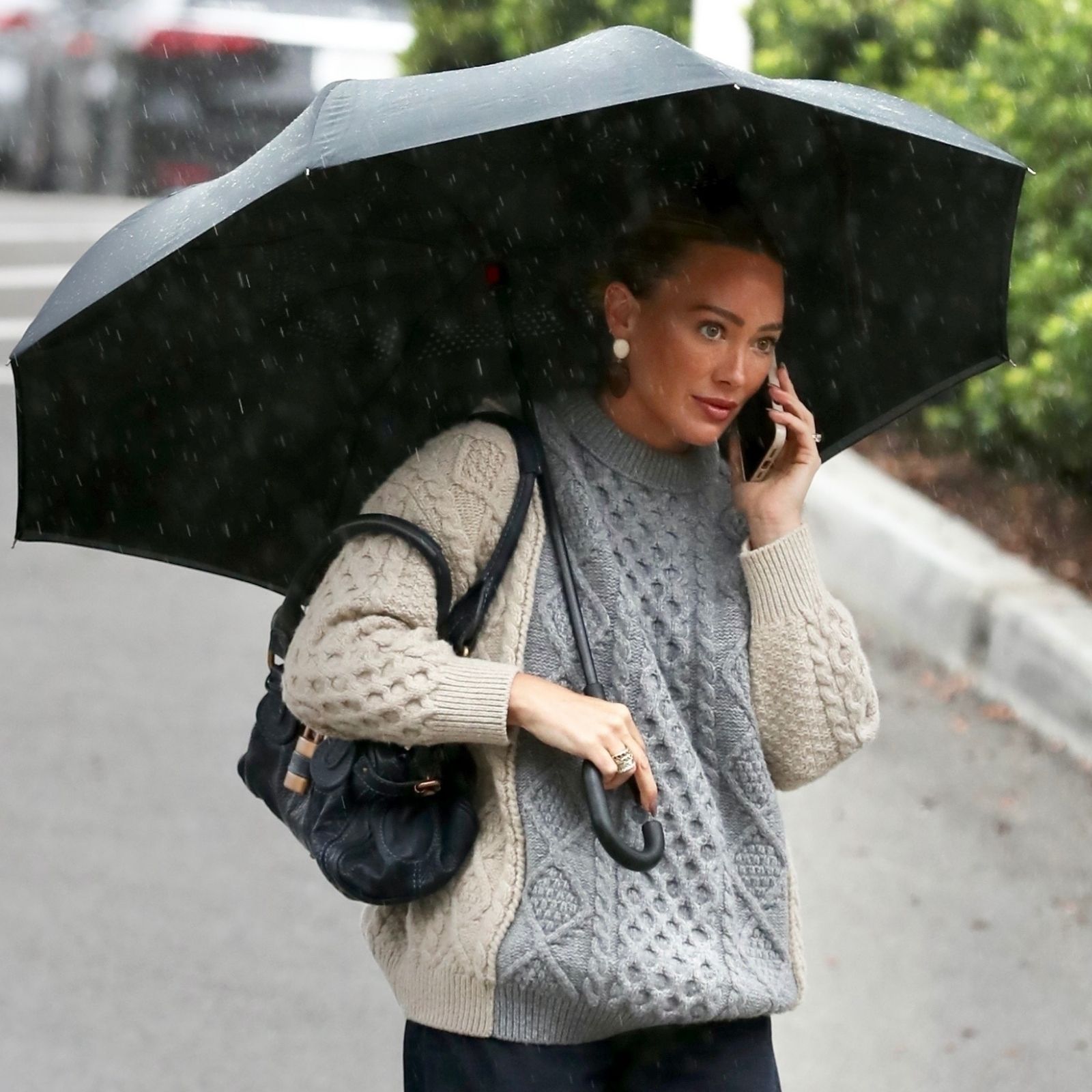 Hilary Duff carries a black umbrella