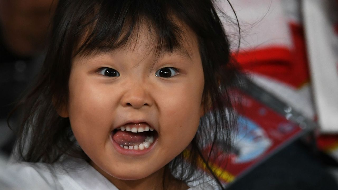 A young Japanese fan cheers during the opening ceremony at the Tokyo Stadium