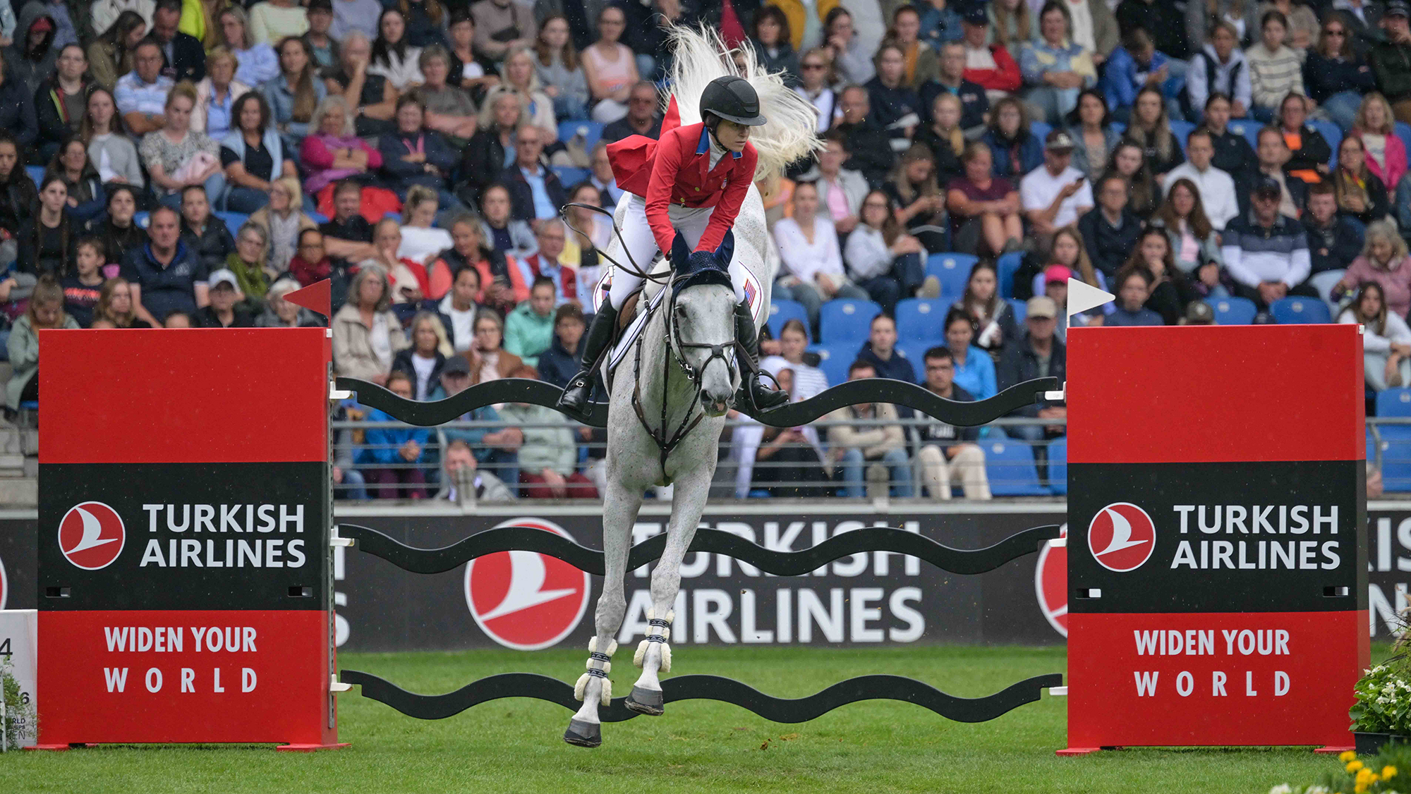 Katie Dinan and Out Of The Blue SCF jump a wavy black plank fence at the showjumping World Championships in Aachen.