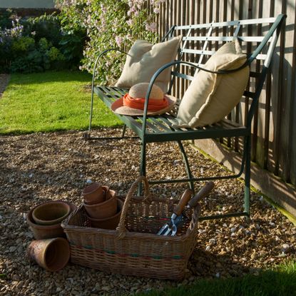 A garden with a bench and a basket filled with tools
