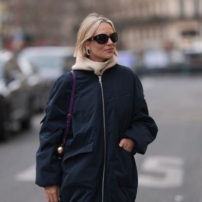 A woman with a blonde bob wearing an autumnal outfit and scarf