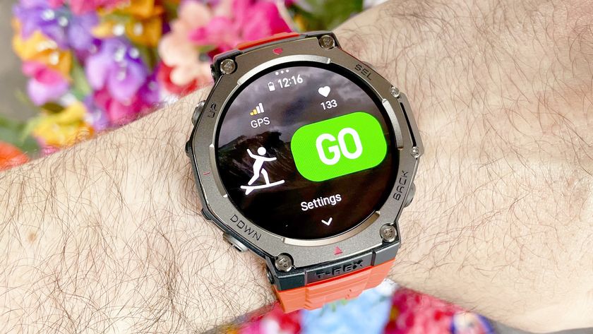 The Amazfit T-Rex 3 shown close-up on a user&#039;s wrist with the snorkeling and surfing workout tracking modes displayed; colorful flowers are out of focus in the background