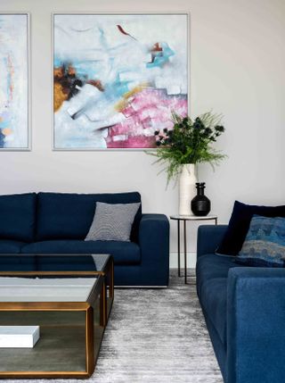 Modern living room with wall art and blue sofas by PROJECT AZ
