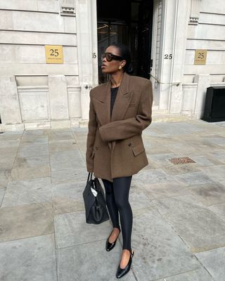 Marilyn Nwawulor-Kazemaks wears a brown blazer, leggings, and black slingback flats.