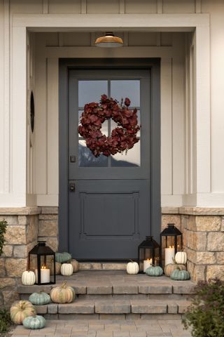 A porch with a wreath and pumpkins