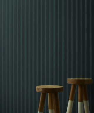 dark teal wall with two wooden stools