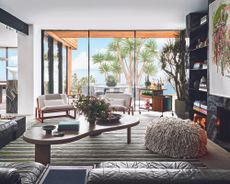 modern living room with striped rug and modern furniture and large window with palm tree outside