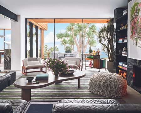 modern living room with striped rug and modern furniture and large window with palm tree outside