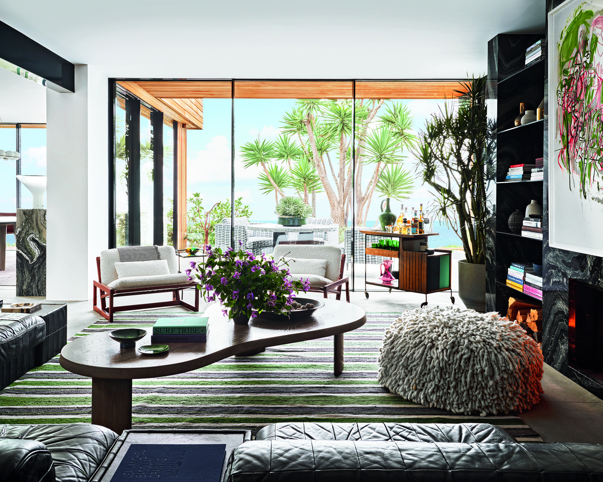modern living room with striped rug and modern furniture and large window with palm tree outside