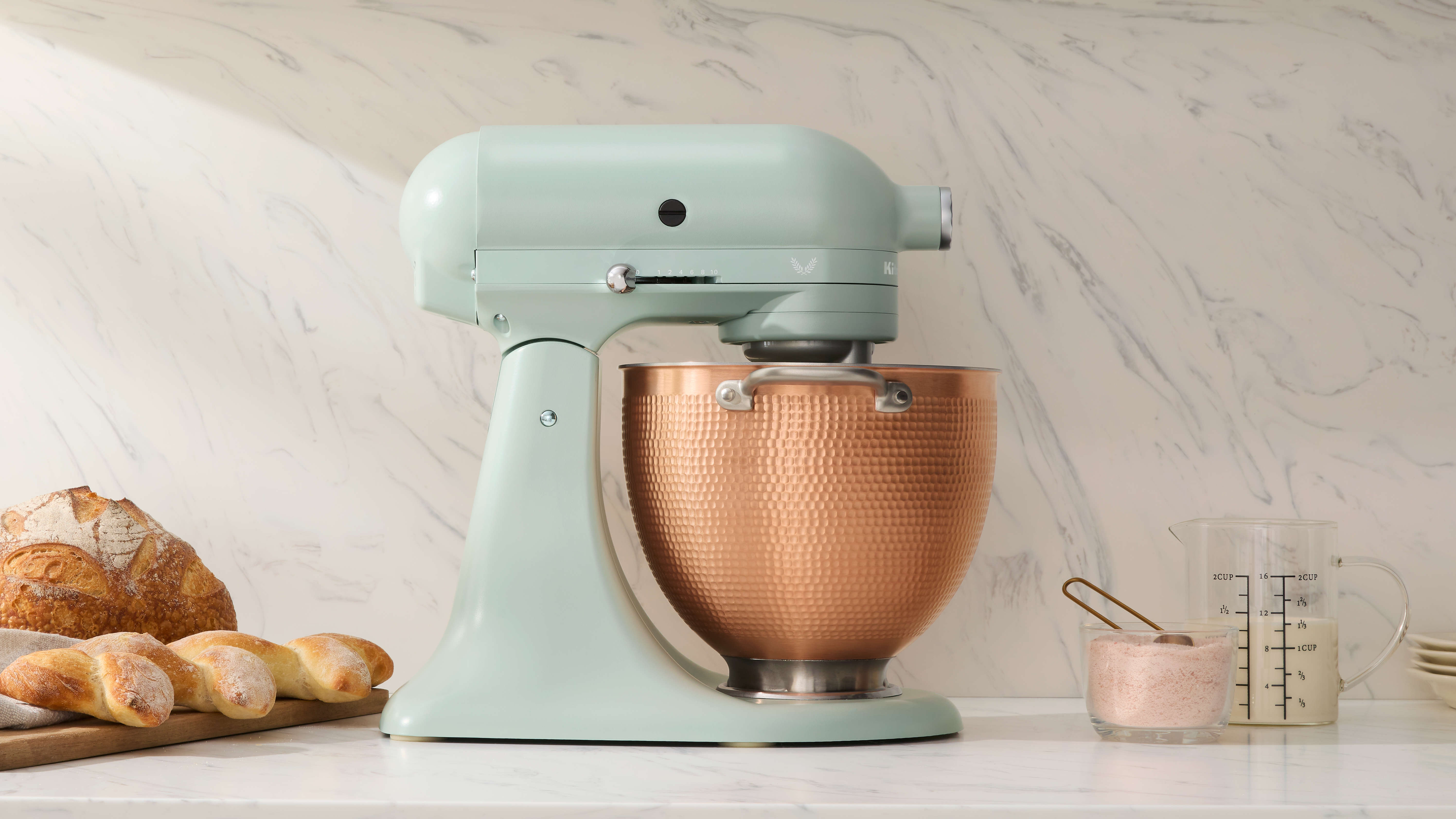 Light green kitchenaid stand mixer with a copper mixing bowl with a