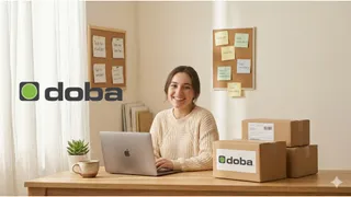 An e-commerce seller sat at home with their laptop near some boxes bearing the Doba logo