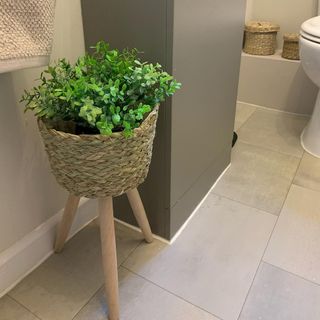 a scandi style cloakroom with grey vinyl flooring, a grey vanity unit and a pot plant in a basket on wooden legs