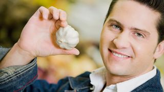 Man grimacing holding a bulb of garlic