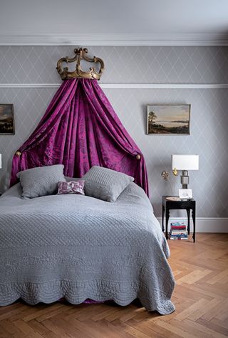 Grey bedroom with pink canopy and herringbone wooden flooring