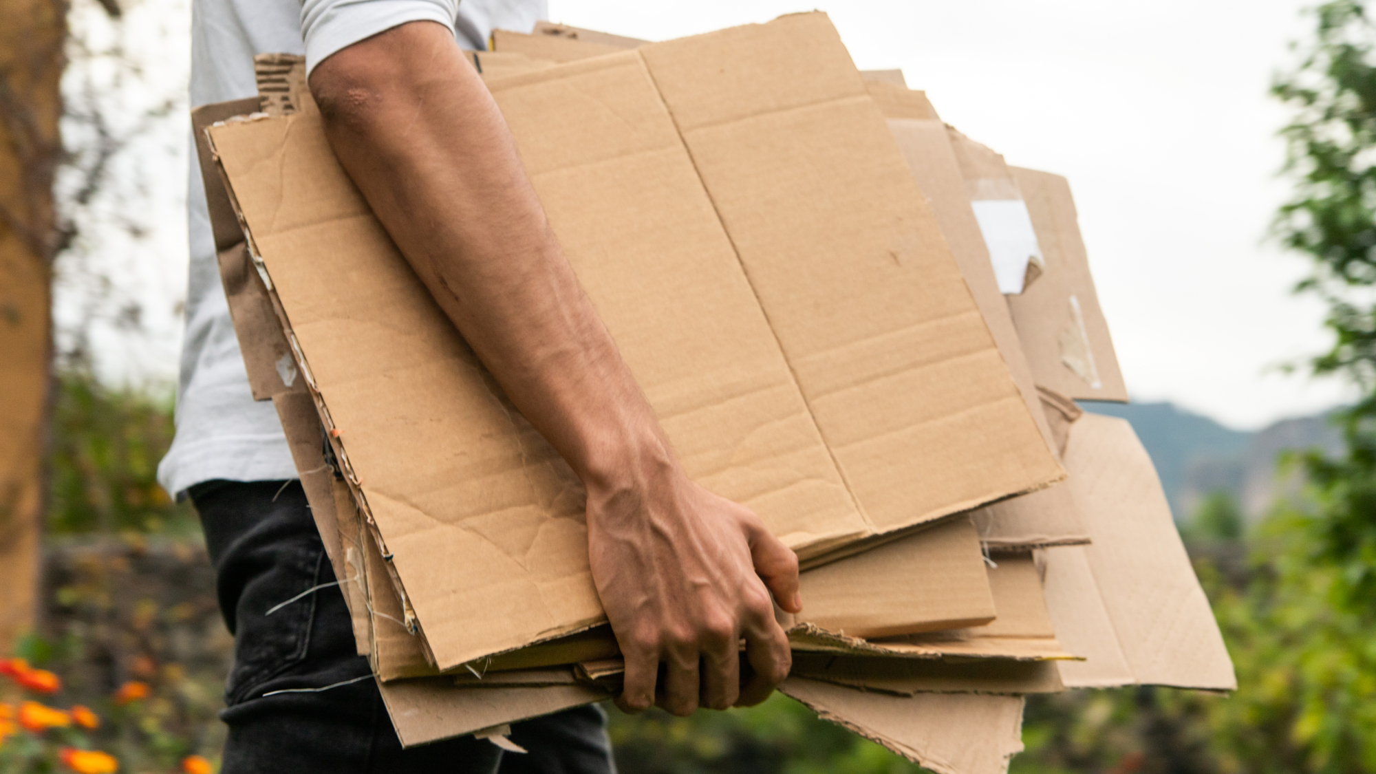 man carrying stack of cardboard outside