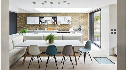 wooden dining room table and chairs and wooden flooring, with orange and white wallpaper and pendant lighting 