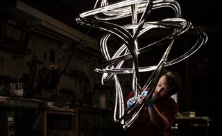 A man working on a twisted metal light sculpture