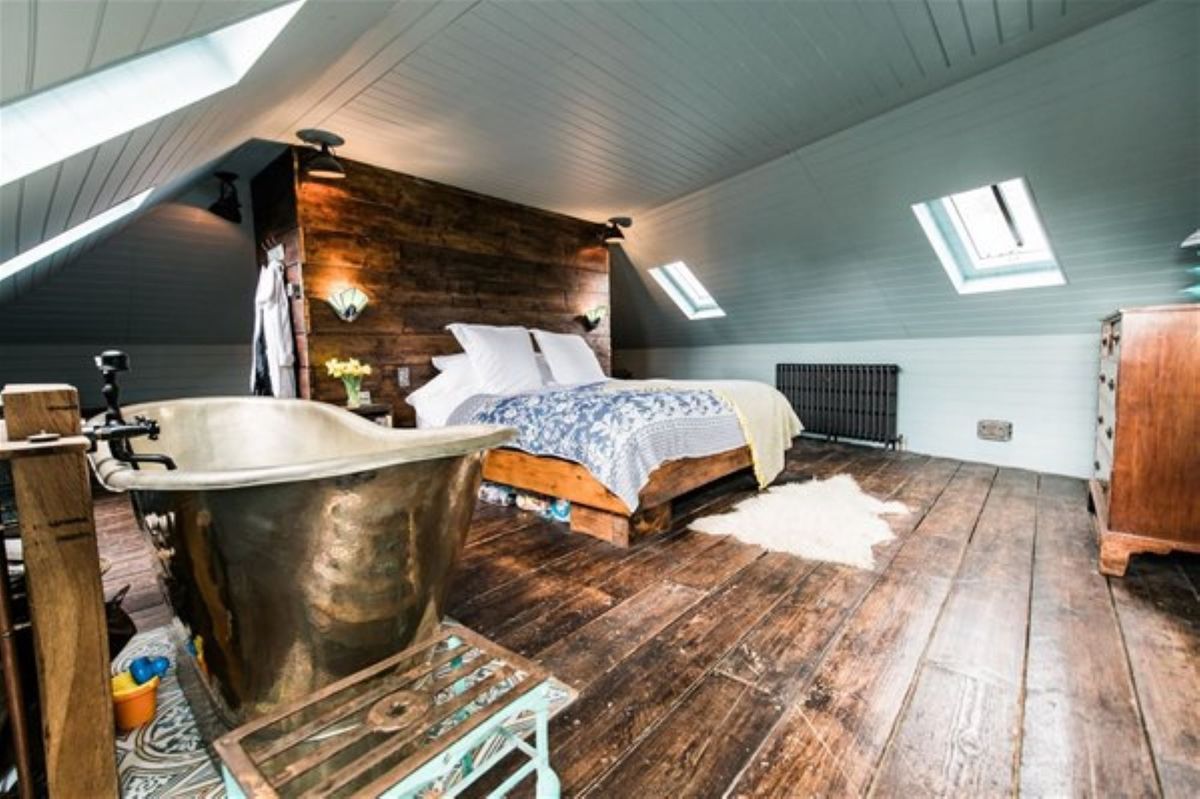 The bedroom has wooden flooring and a copper bath on the side of the room