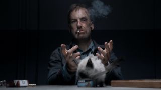 Bob Odenkirk smoking cigarette with cat in front of him in Nobody 
