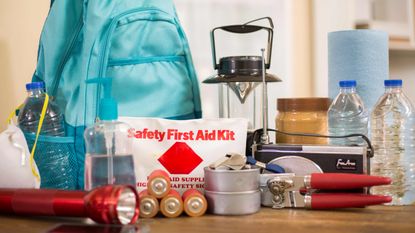 Emergency supplies on a table, including batteries, a flashlight and lantern.