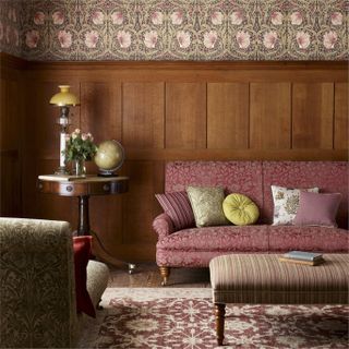 Wooden wall panelling with patterned wallpaper, complete with dusk pink printed sofa and lighting and period decor