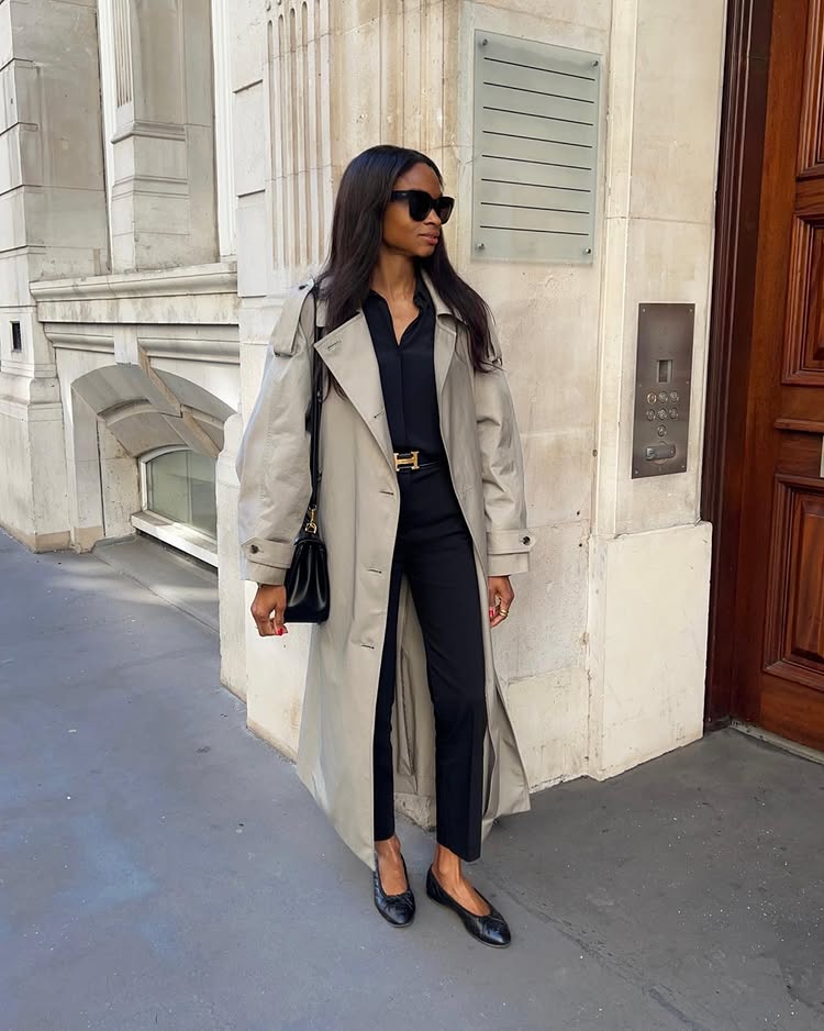 @symphonyofsilk wears a beige trench coat with cropped trousers and a black shirt