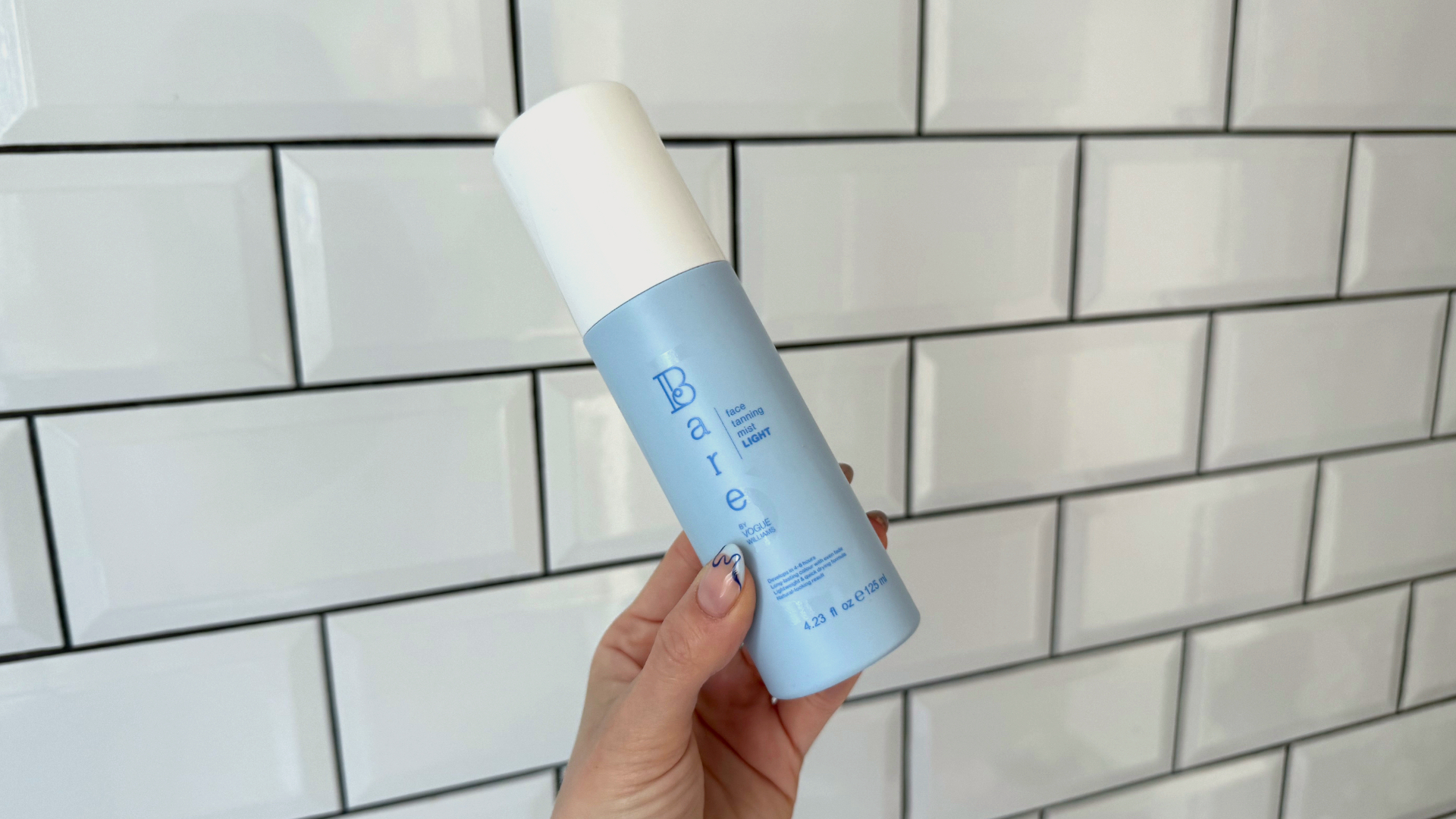 Original image showing a handheld view of the Bare by Vogue Face Tanning Mist in front of a white tiled background