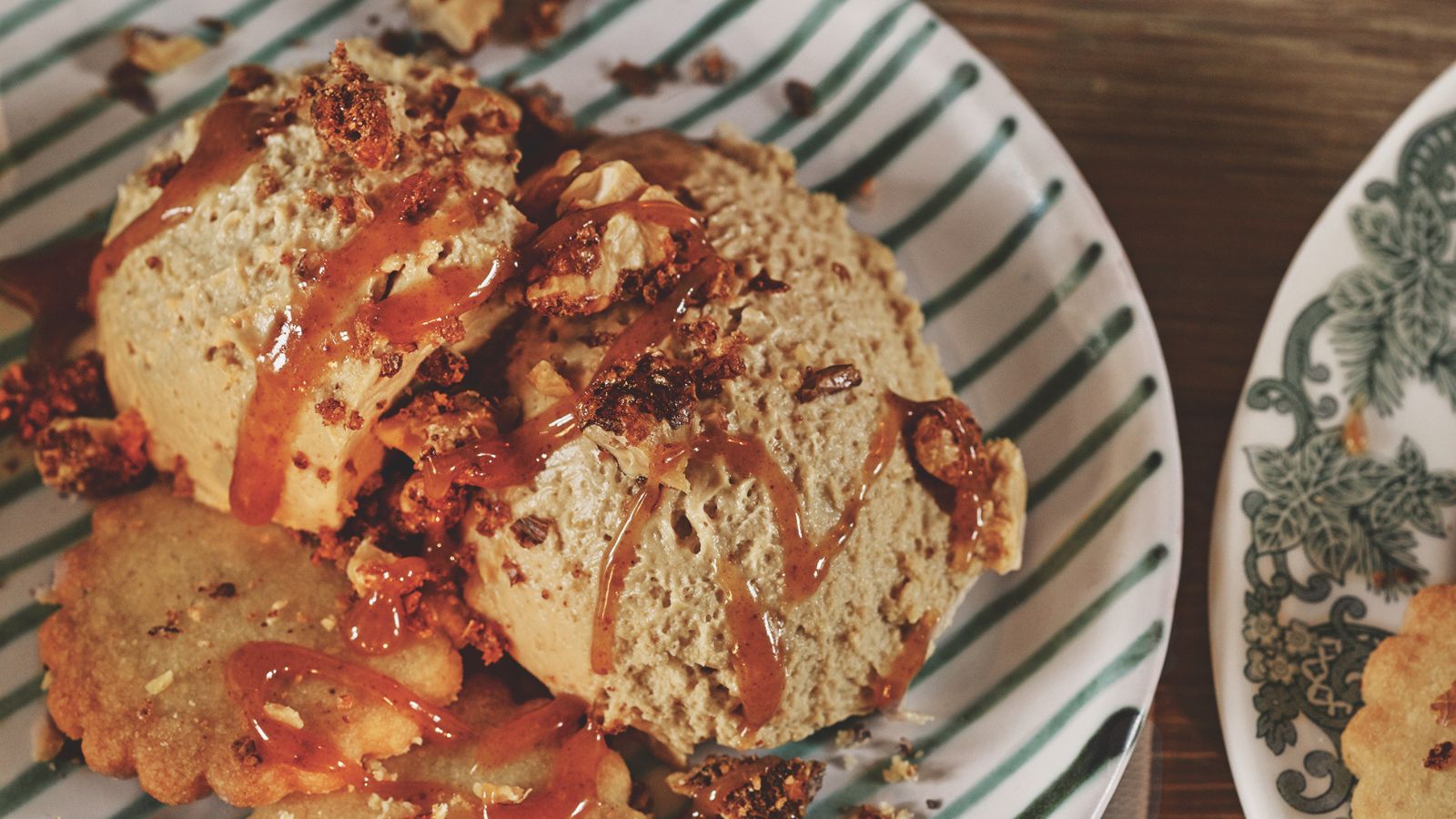 Butterscotch mousse with sauce and biscuits on a green and white striped plate
