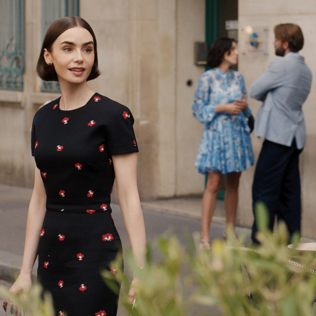 lily collins as emily wearing a black and red polka dot dress turning around her shoulder surprised on a european street in season 5 of emily in paris
