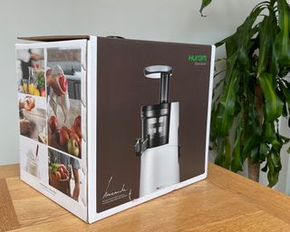 Hurom H-AA slow juicer in box on wooden dining table