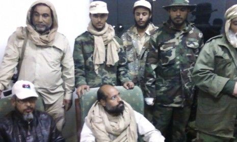 A mobile phone picture taken by one of his guards shows Gadhafi&amp;#039;s son, Saif al-Islam, sitting with his captors in Libya&amp;#039;s Obari airport.