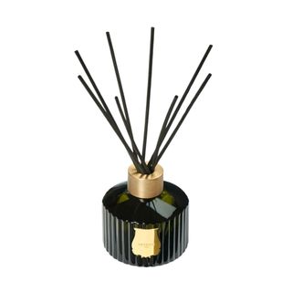 A black glass reed diffuser with gold detailing and black reeds