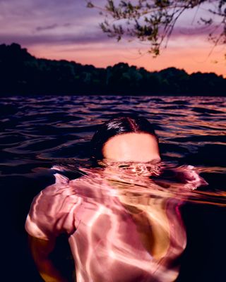 A woman floats just below the surface of the ocean at dusk