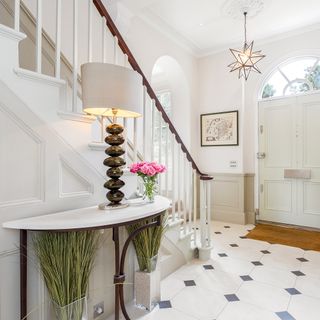 white entrance hall with staircase and lamp light