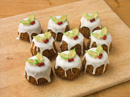 Set of nine mini Christmas cakes with drizzle icing and holly decoration