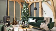 Christmas tree in Scandi style living room with green couch, coffee table, and wooden accents