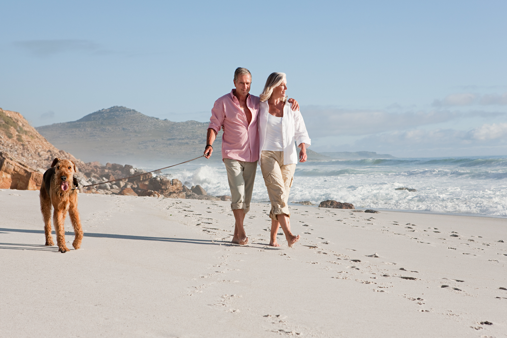 Couple walking dog by the sea