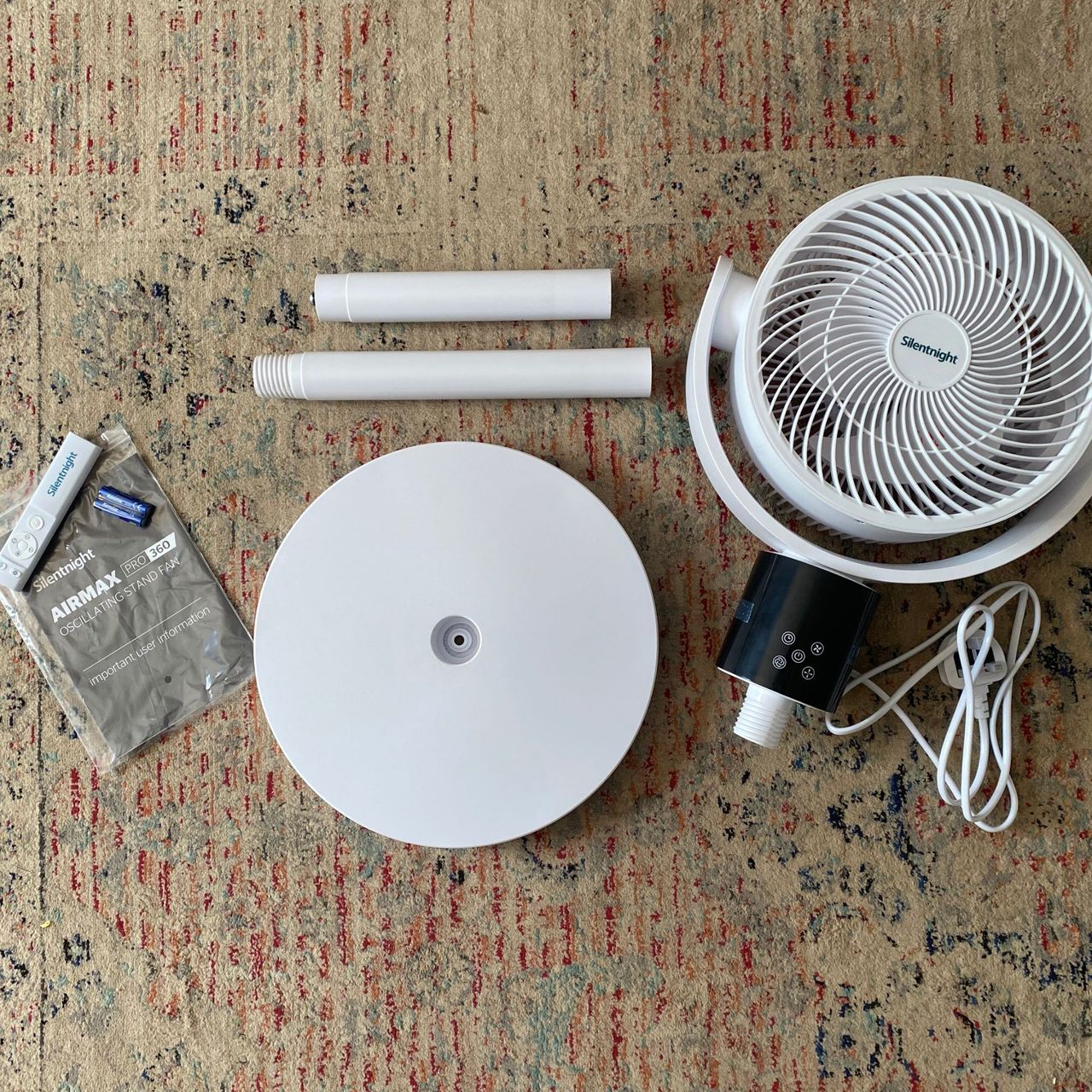 The individual parts of the Silentnight Airmax Pro360 Pedestal Fan before assembly, laid on a patterned rug