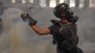 Protestor throwing tear gas grenade