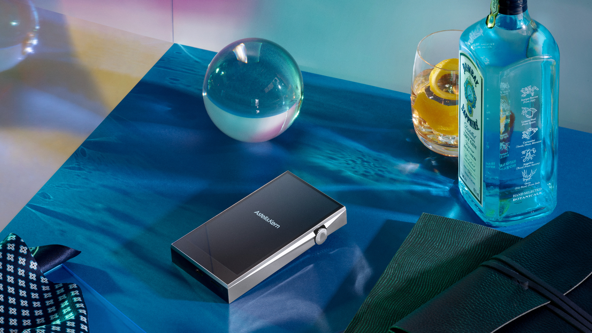 Astell & Kern's A&ultima SP3000 player next to a bottle of gin, on a blue table