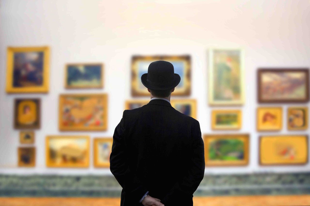 silhouette of a man looking at framed art on a wall