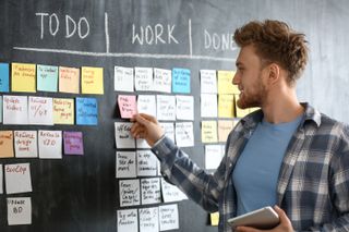 Scrum master in front of a board with jobs written on sticky notes