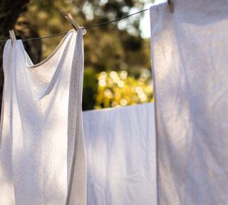 A set of three white cloths being hung on clothes line outside