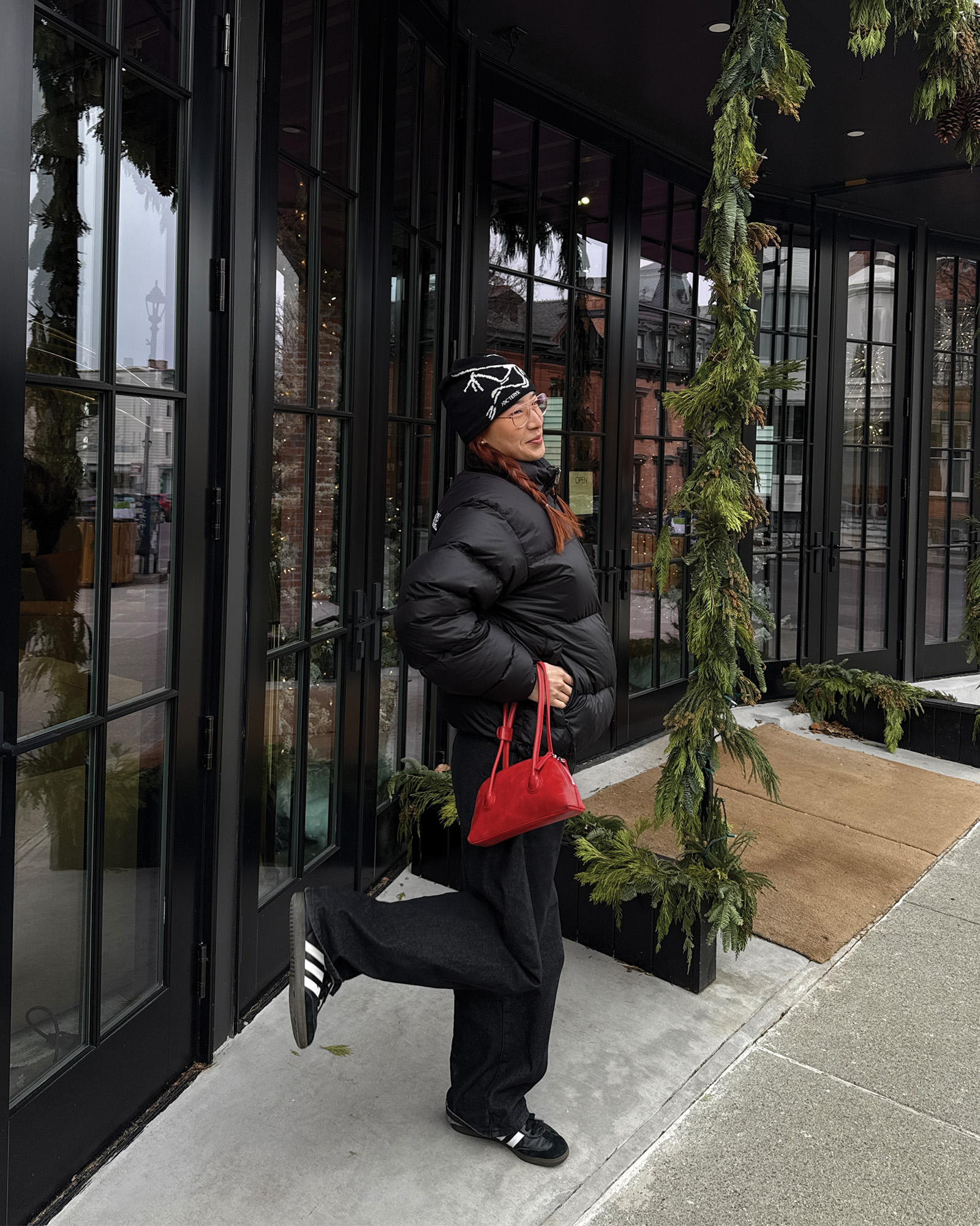 Who What Wear Editor in Residence Kristina Ang wearing a beanie, puffer jacket, and Adidas sneakers.