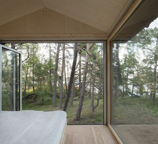 A frame cabin inside looking out to wooded views