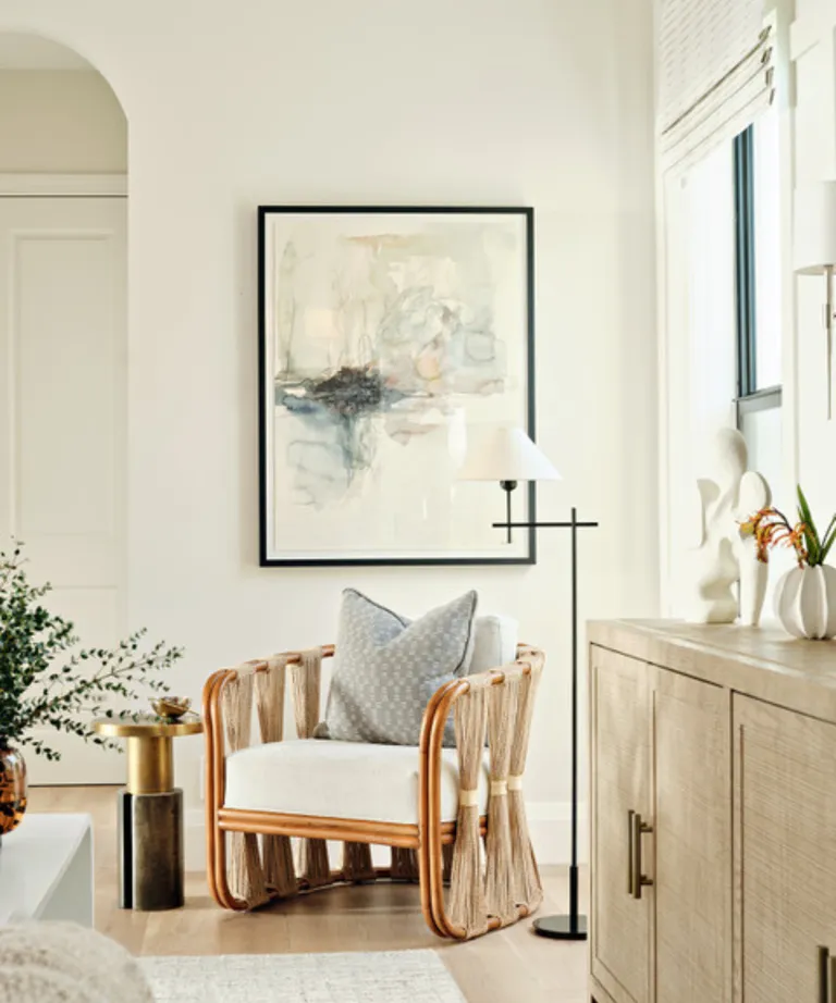 Armchair in corner of cozy neutral living room space with a flourish of surrounding greenery