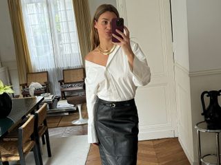 French fashion influencer @annelauremais wearing a chic outfit featuring staple Parisian fashion items for 2025, including an on-trend leather skirt and skinny belt.