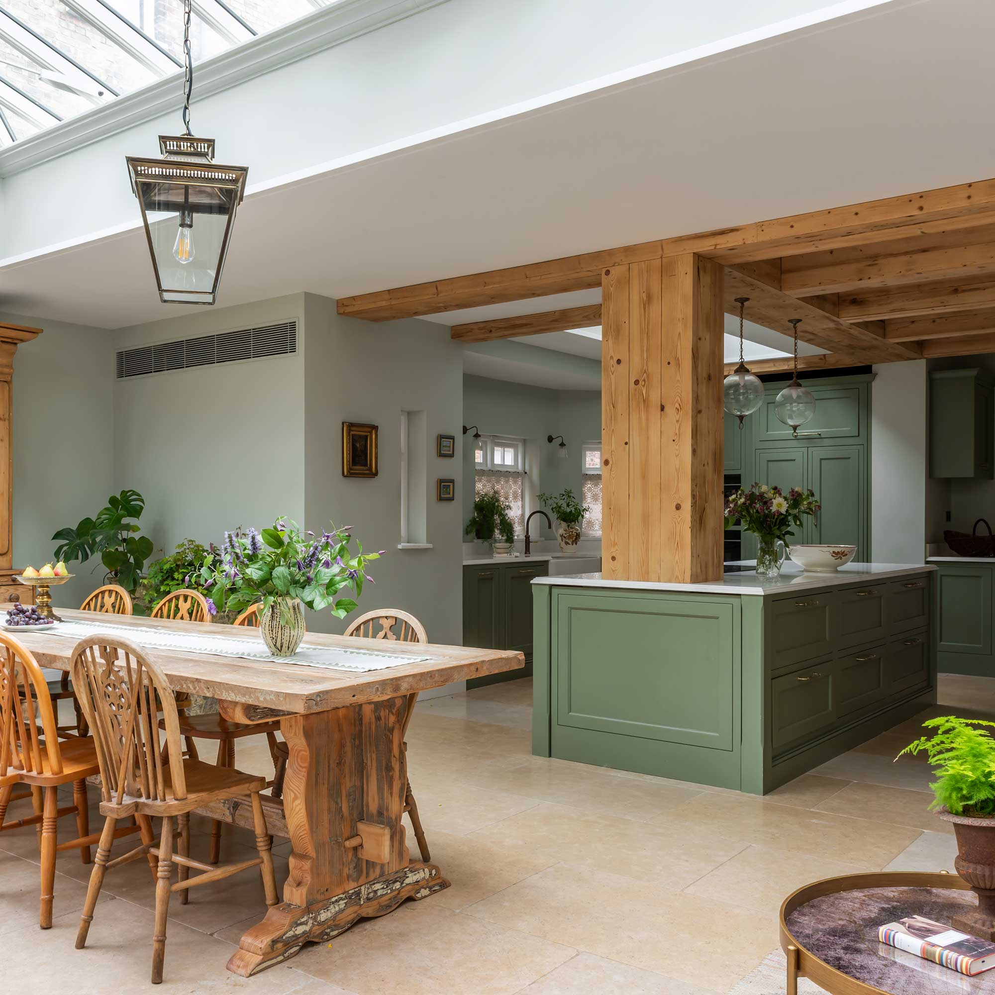 view from orangery dining room extension with rooflight through to green kitchen with wooden beams